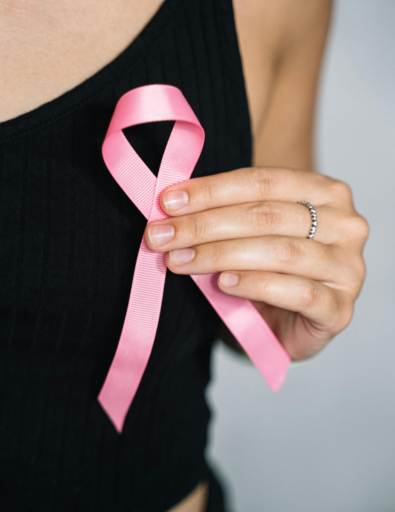 Personne tenant un ruban rose de sensibilisation au cancer de sein, symbole de la campagne d'Octobre Rose.
