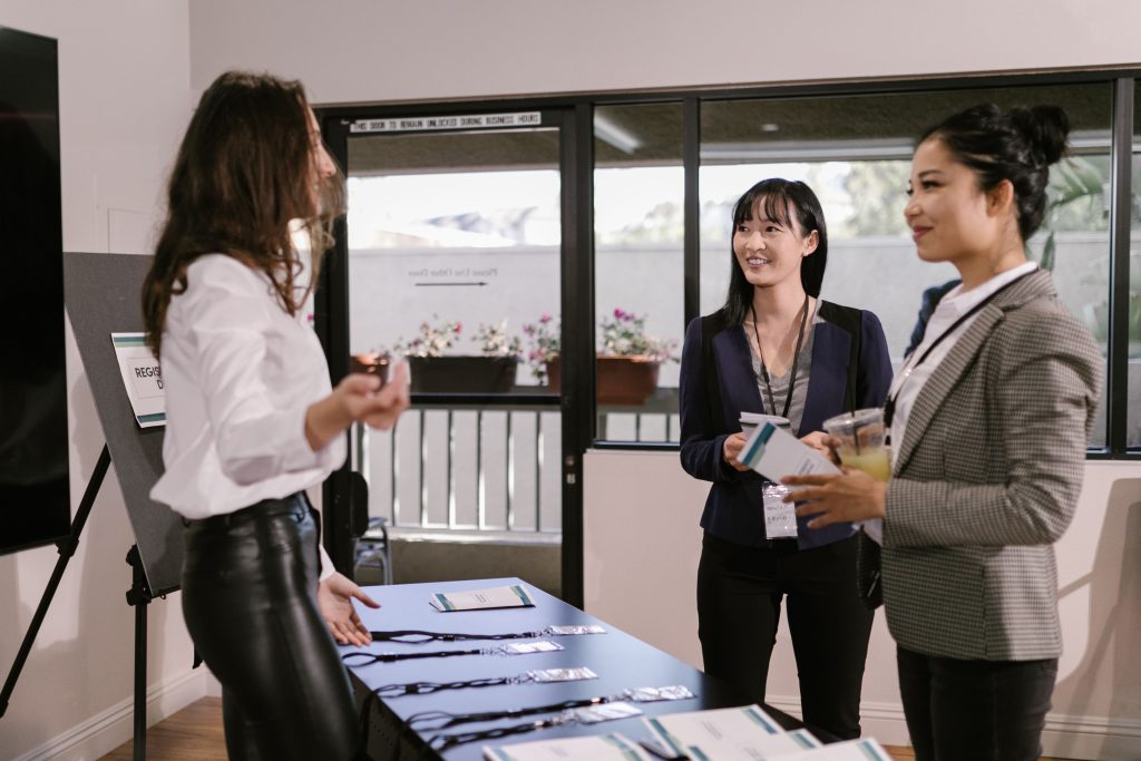 Professionnelles échangeant à un comptoir d'inscription lors de l'accueil des participants à un événement professionnel