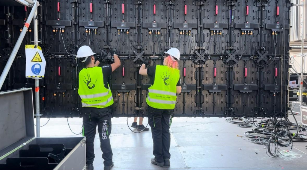 Technicien installant un écran numérique sur une scène pendant la préparation d'un événement