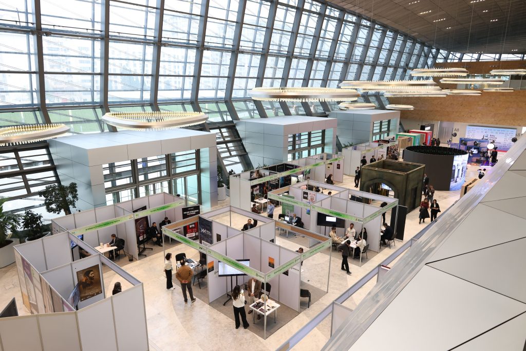 Visiteurs circulant entre les stands dans un hall d'exposition.
